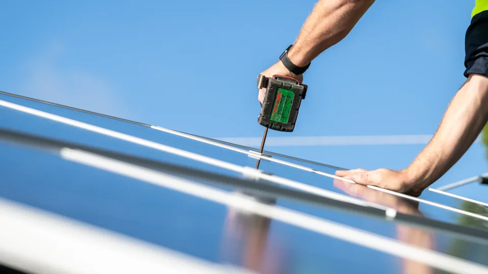 Electrician fitting a solar panel on a roof
